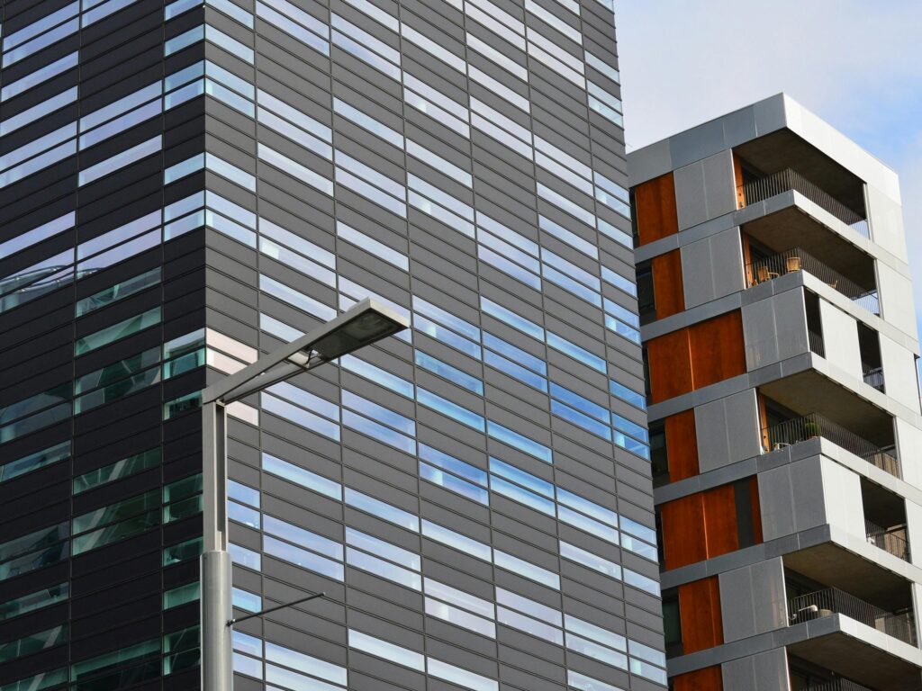 Low angle view of a modern glass office building and residential structure in daylight.